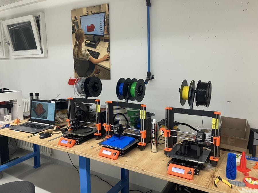 Hier sieht man drei ganz moderne 3D-Drucker, die gerade alle mit ausdrucken beschäftigt sind.